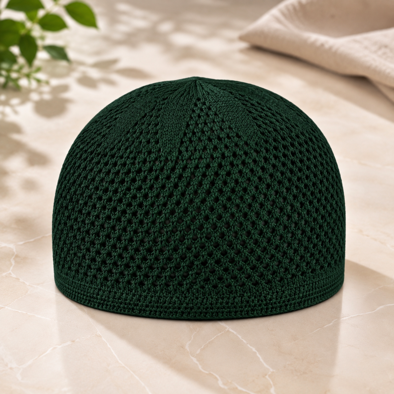 Dark green knit kufi prayer cap on marble